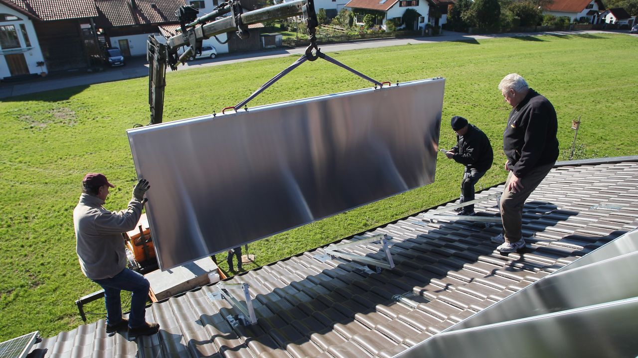 Workers in Wessling, Germany, install solar power modules on the roof of a home.