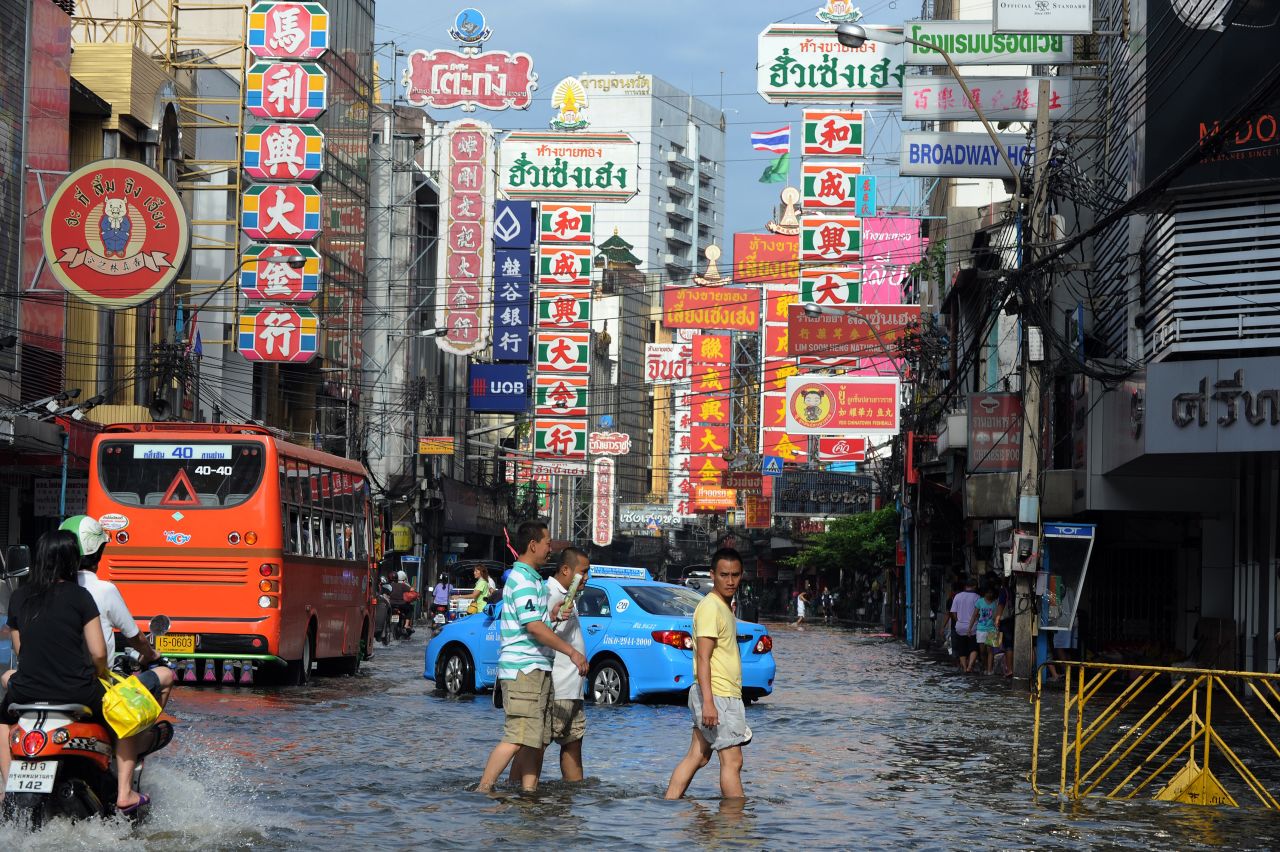 Thai residents walk in floodwaters along a street in the Chinatown section of Bangkok.