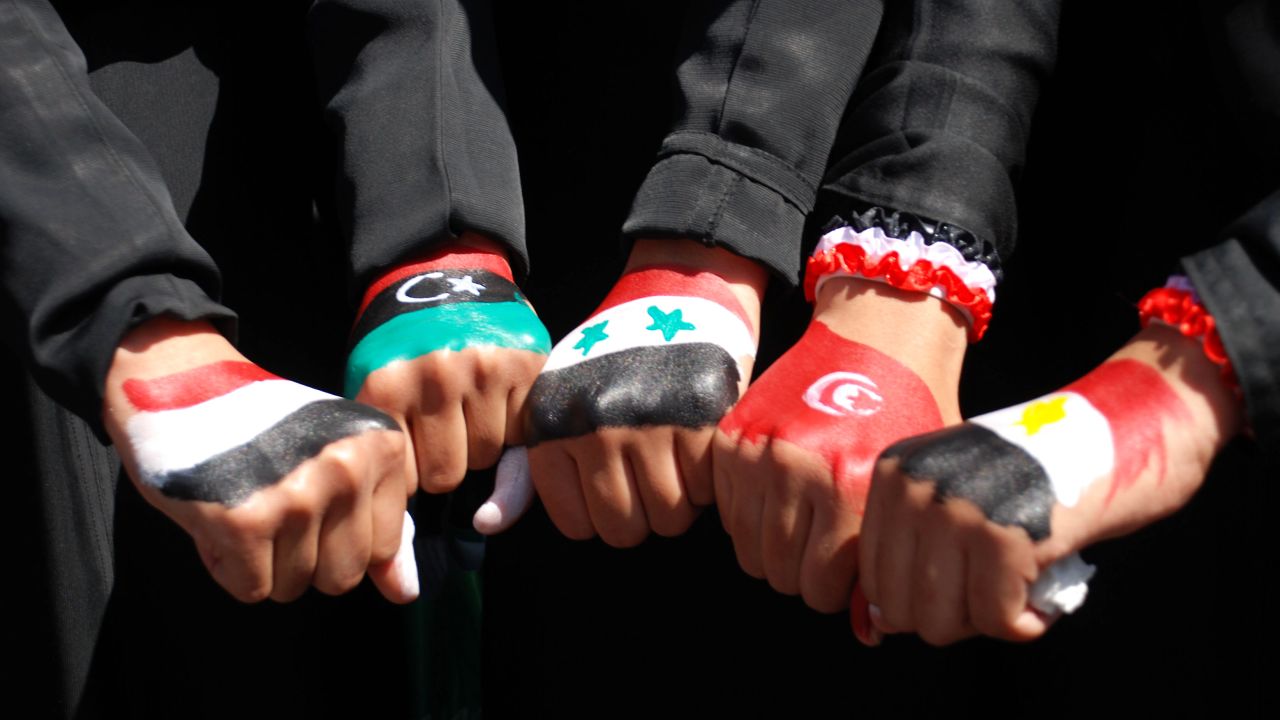 Yemenis women show off their fists paintd in the colors of five national flags: Yemen, Libya, Syria, Tunisia and Egypt.