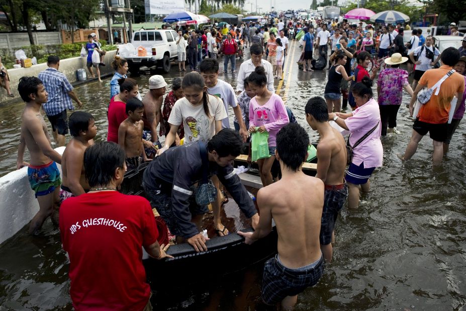 Residents evacuating their neighborhoods get off a rescue boat near the Chao Praya River.