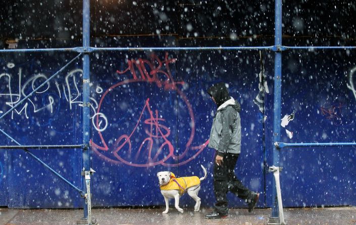A man walks his clothed dog through the snow in Manhattan.