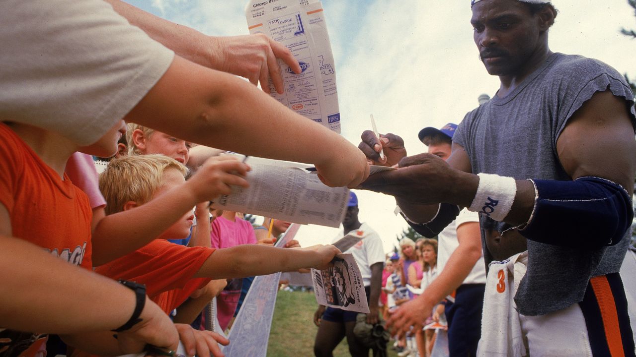 Walter Payton, #34 of the Chicago Bears, signs autographs during training camp in 1987