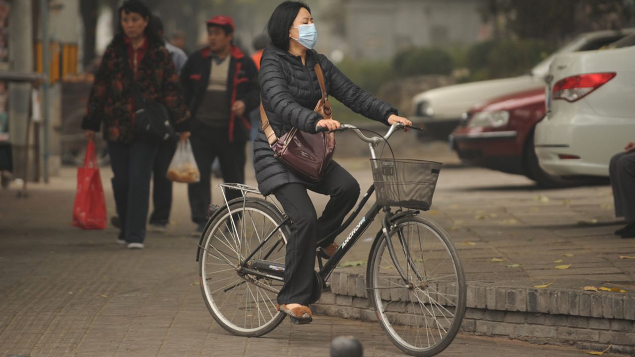 A woman tries to counter poor quality air by wearing a mask as she rides a bicycle in Beijing on October 31, 2011.  