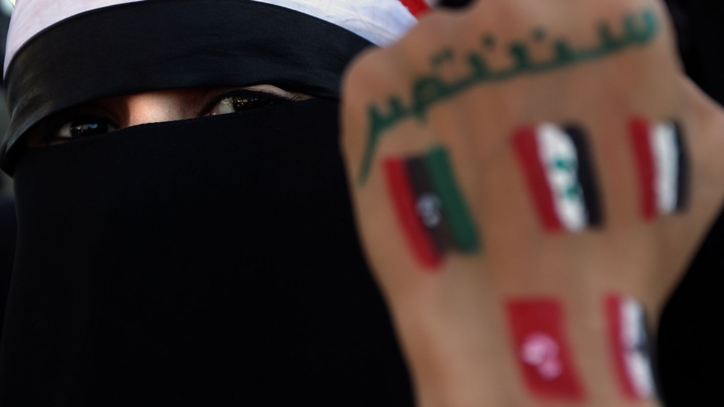 A Yemeni woman shows her fist with flags of Arab countries who took part in the Arab Spring. 
