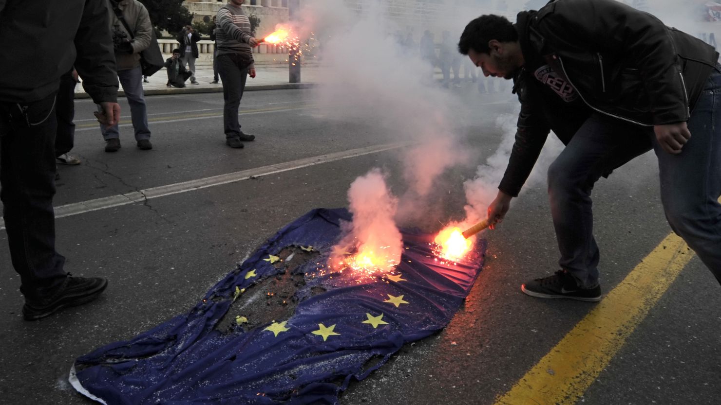 A Greek student sets fire to the flag of the European Union. 