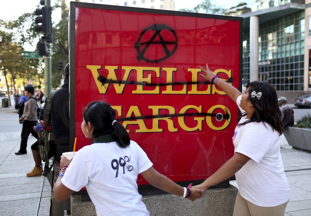 Protesters run by a defaced Wells Fargo bank sign during Occupy Oakland's general strike. Wednesday's incidents involved graffiti and smashed windows, police say.