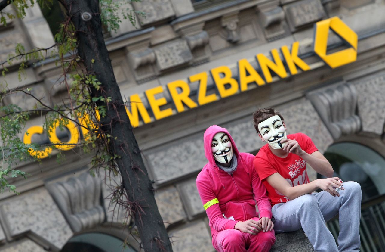 Demonstrators wearing "Vendetta" masks sit in front of a Commerzbank branch in Frankfurt on October 29.