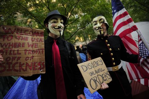 Masked Occupy Wall Street supporters hold signs at Zuccotti Park in New York on October 30. 