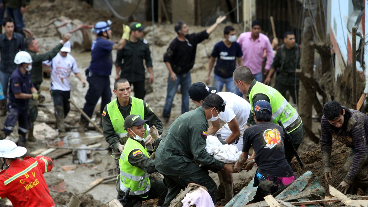 Residents, police officers and rescue workers retrieve the body of a victim in Manizales, Colombia, on Saturday.