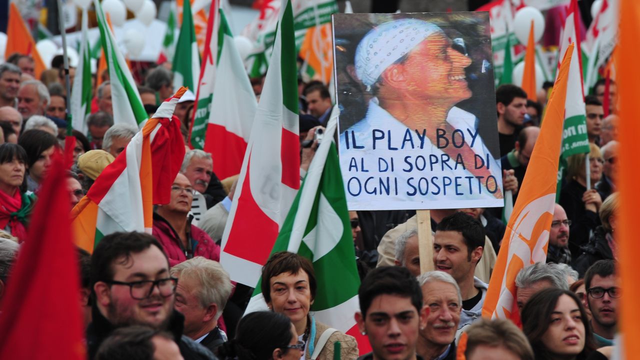 Los manifestantes protestan contra el gobierno de Berlusconi en 2011, con un cartel que dice 
