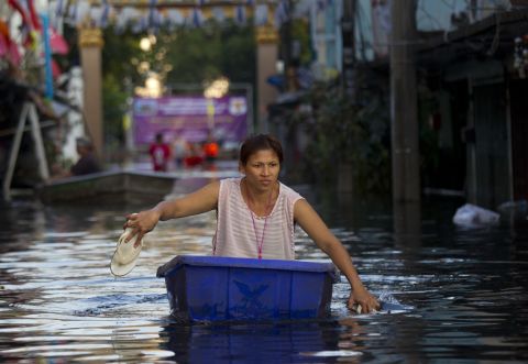 A Bangkok resident uses her footwear as paddles as floodwater moves towards central Bangkok, November 7.