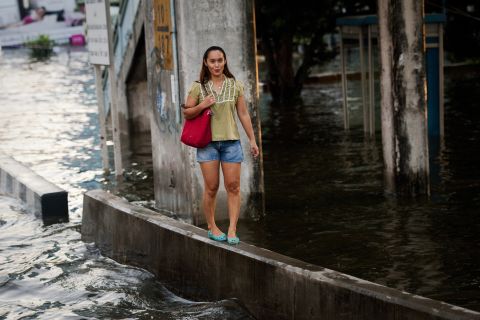 A woman walks along a wall to avoid floodwater in Bangkok, Thailand, November 7.