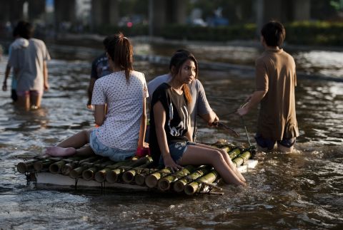 People sit on a bamboo raft to cross the floodwaters in Lat Phrao shopping and business district in Bangkok, November 7.