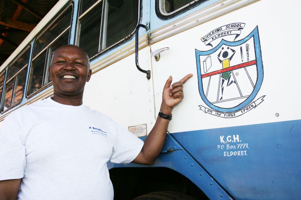 Keino poses beside a bus with the mural of his primary school in Eldoret, Kenya.