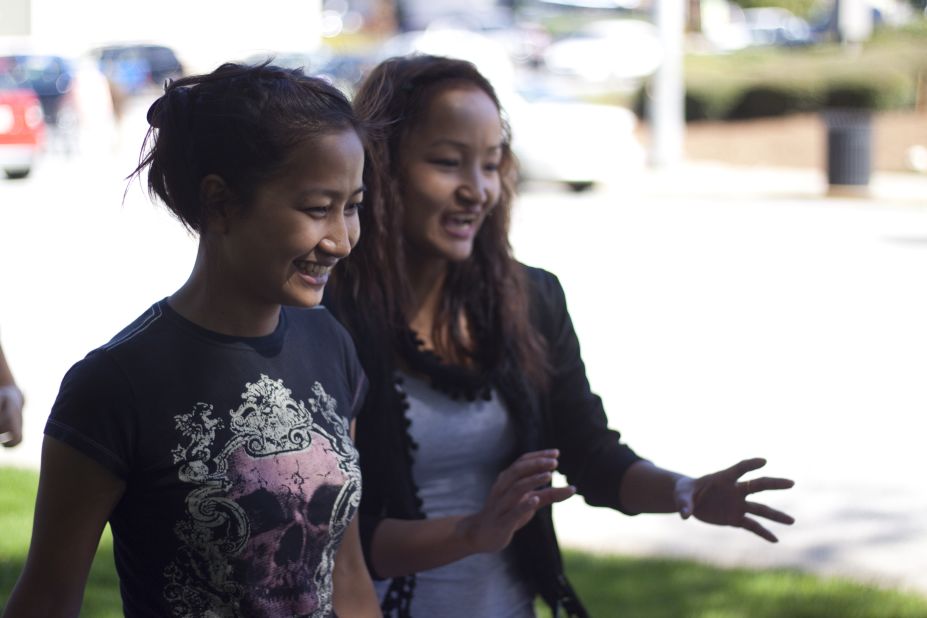 Rita, left, laughs with her older sister Melody as they walk back to class. Rita and Melody have been in the United States for one year.