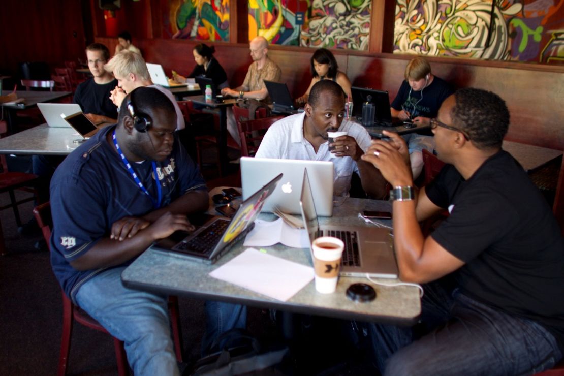 NewMe co-founder Wayne Sutton, center, works on his laptop at a coffee shop with fellow entrepeneurs.