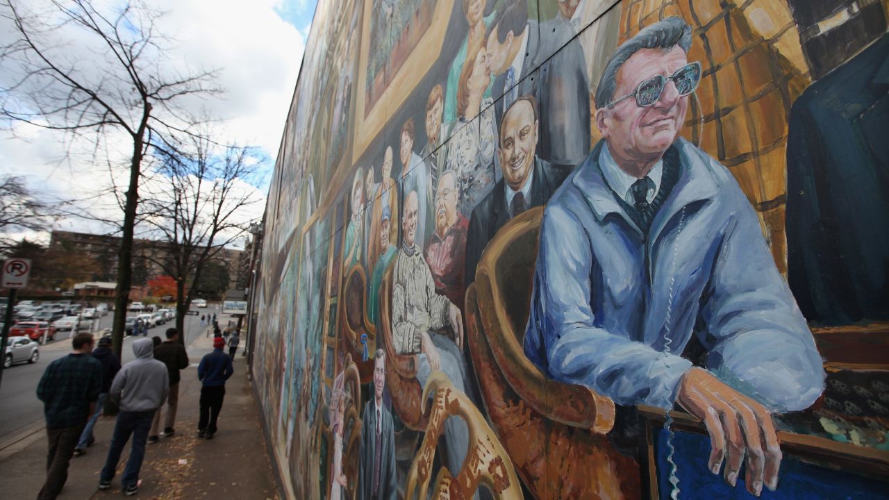 In State College, people walk by "Inspiration," a mural that depicts Joe Paterno, fired over the sex assault case of Jerry Sandusky.