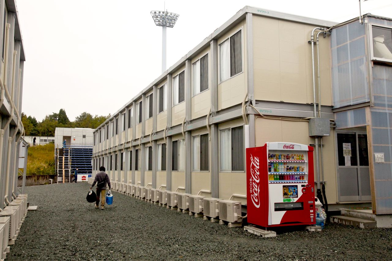 A worker carries his belongings as he walks among the temporary housing structures at J-Village.