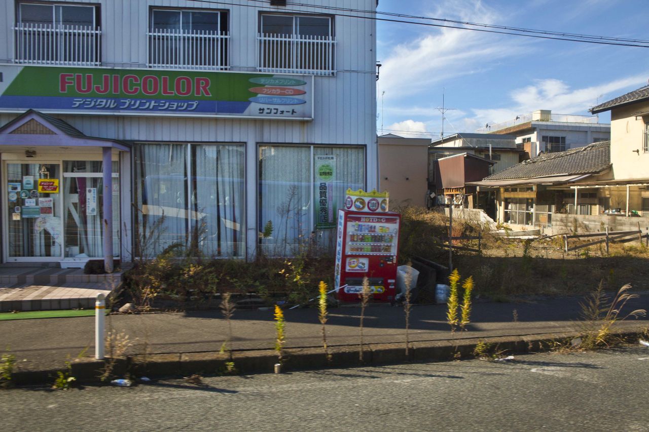 A deserted neighborhood inside the contaminated exclusion zone is visible through the bus window.