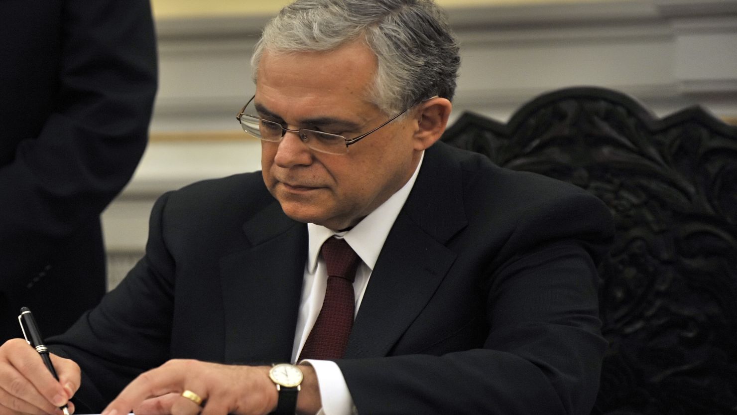 Lucas Papademos signs documents after being sworn in as Greece's new Prime Minister in Athens on Friday.