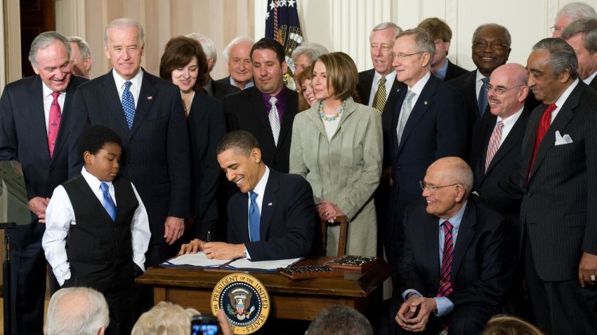 US President Barack Obama, surrounded by lawmakers, signs the healthcare insurance reform legislation during a ceremony in the East Room of the White House in Washington, DC, March 23, 2010. Obama Tuesday signed into law sweeping reforms that will for the first time ensure health care coverage for almost every American. AFP PHOTO / Saul LOEB (Photo credit should read SAUL LOEB/AFP/Getty Images) 