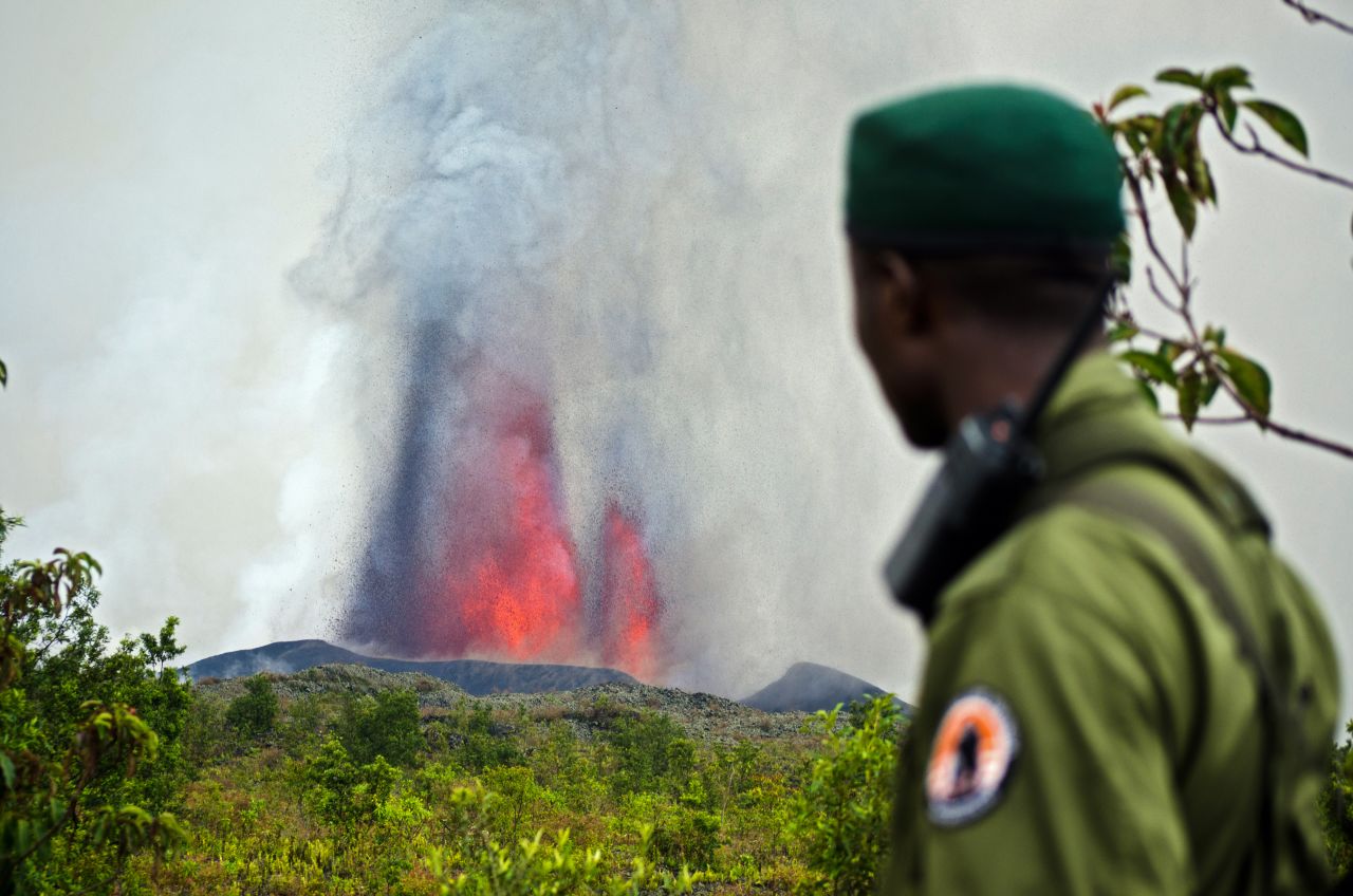 A park ranger looks on as Mount Nyamulagira erupts in front of him.