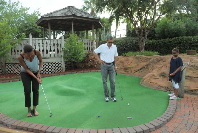 U.S. President Barack Obama and daughter Sasha watch as First Lady Michelle Obama putts on the first hole during a round of mini golf in Florida in 2010. 