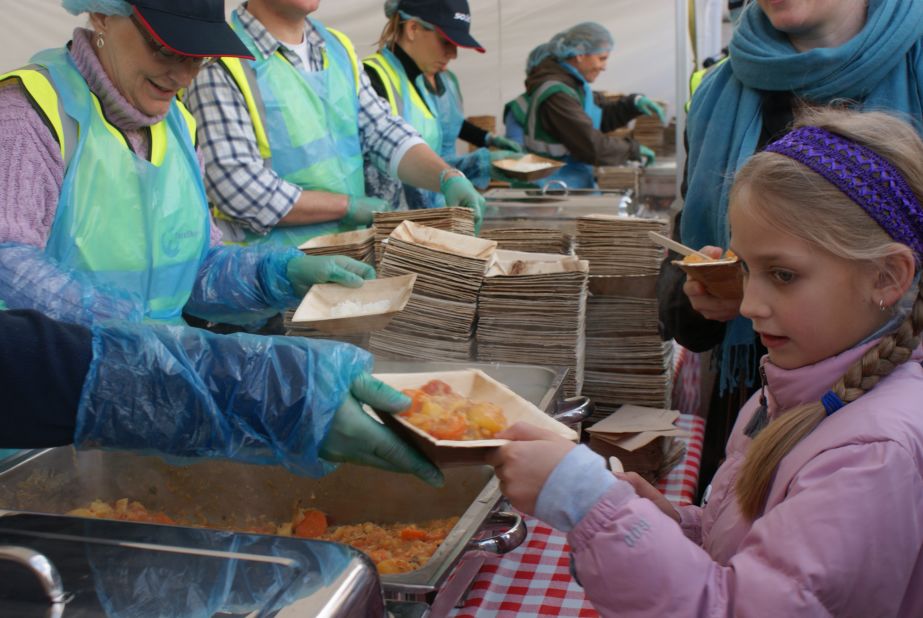 A young girl receieves her free waste curry made from potatoes, carrots, corn, cauliflower amongst other ingredients. Organizers says that an estimated 20-40% of UK fruit and vegetables are rejected even before they reach the shops as they don't match supermarkets' strict cosmetic standards. 
