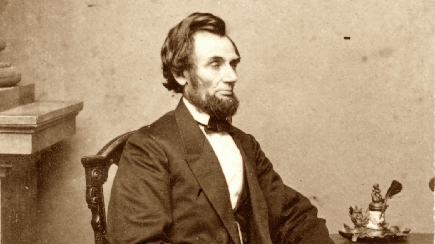 President Abraham Lincoln poses for a portrait next to a table in 1865.
