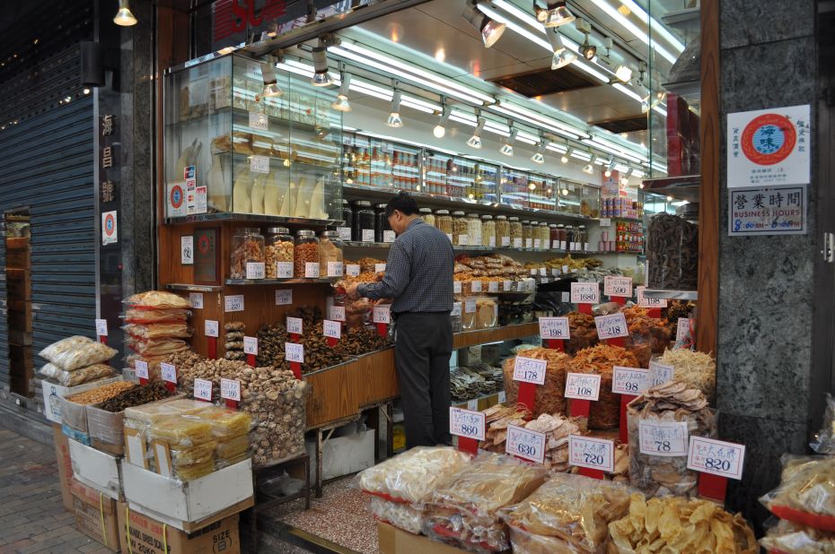 A shop owner works in his dried seafood store, where dried shark fins are displayed in a glass case. 