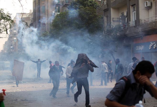 Protesters cover their faces as they flee tear gas fired by police on Sunday.