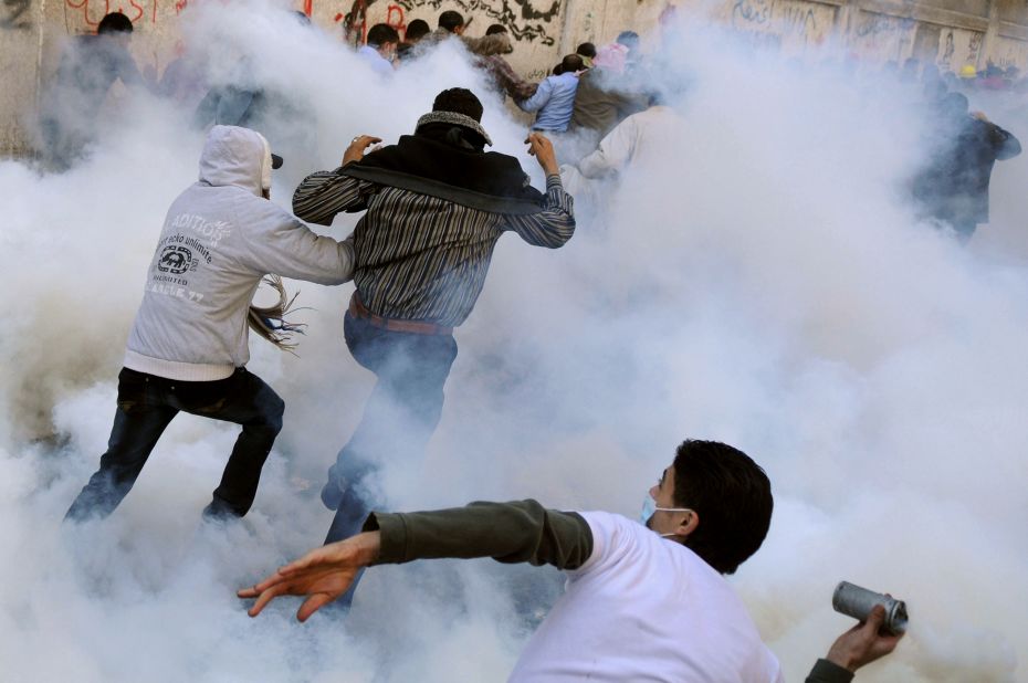 A protester throws a tear gas canister back toward security forces Monday during clashes in Tahrir Square.