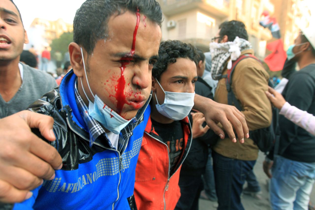 A protester bleeds as he is helped away from fighting Monday in Tahrir Square.