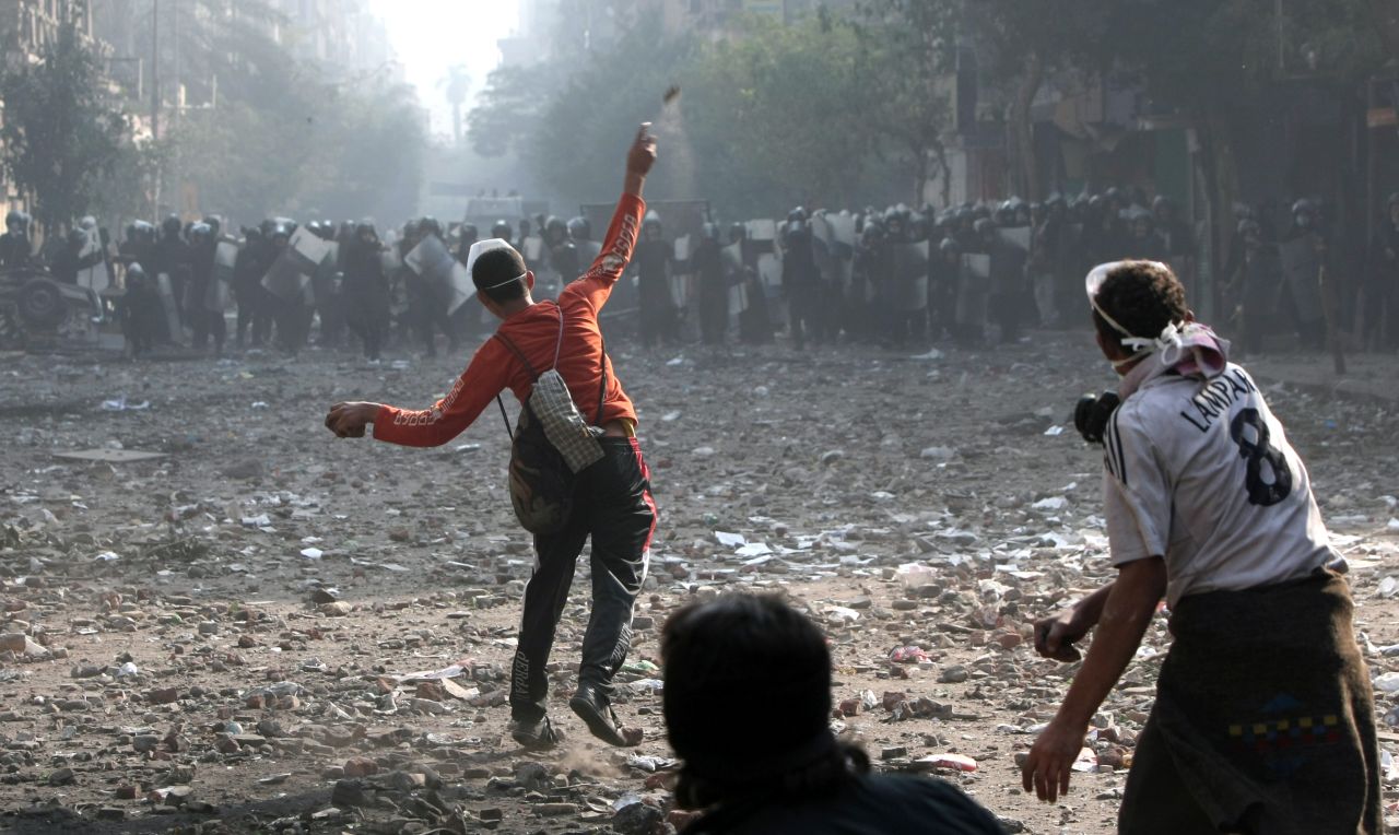 A protester hurls rocks at a line of riot police on Wednesday, November 23,  near Tahrir Square in Cairo. 