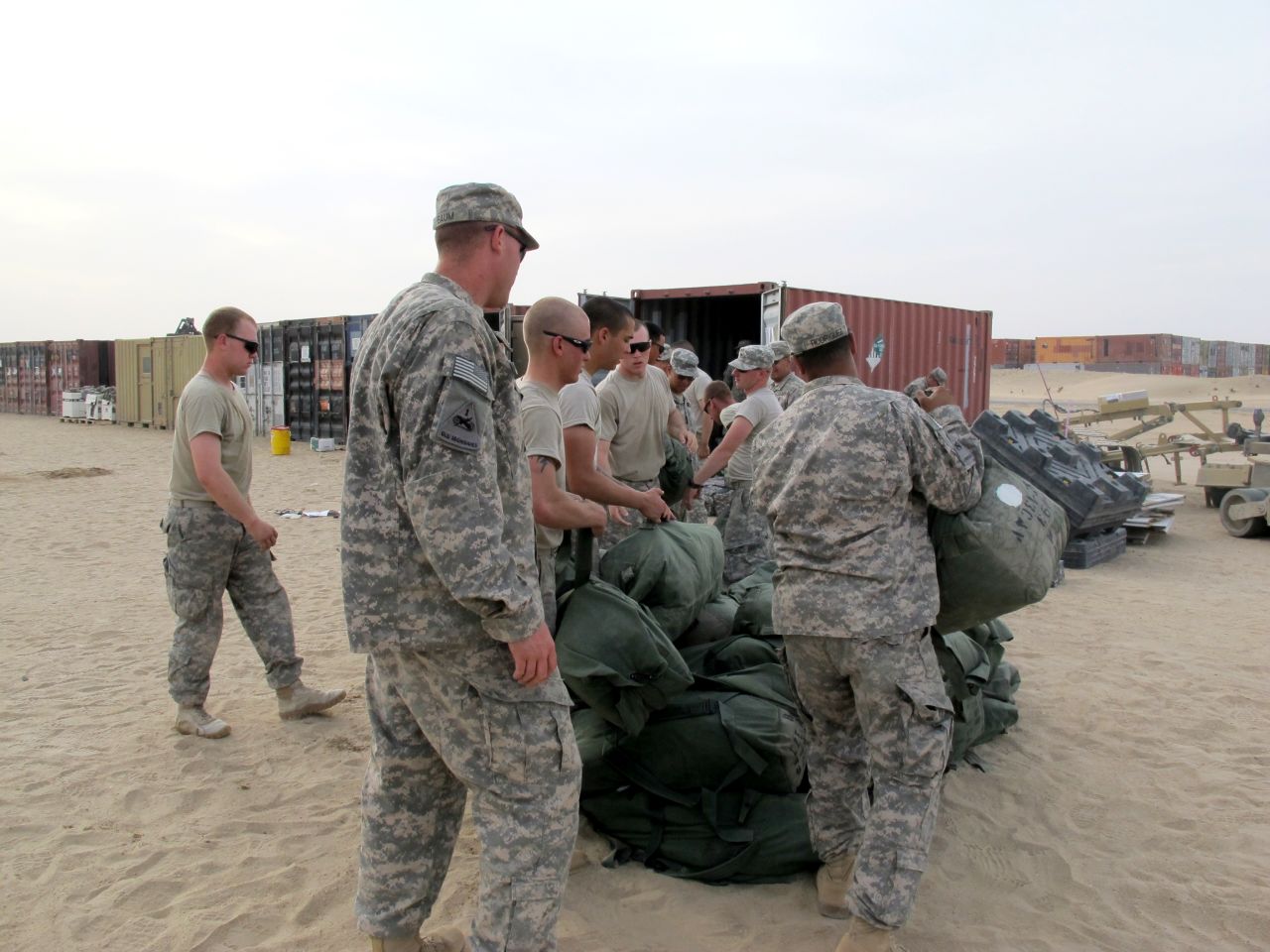 Soldiers load their duffle bags onto a shipping container in Kuwait. The road home for most troops requires them to cross from Iraq into Kuwait, where they turn in equipment before starting the journey back to the United States.