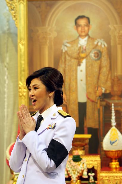 Yingluck Shinawatra is Thailand's first female Prime Minister and sister of former Thai leader, Thaksin Shinawatra. Here she is waiing which is a traditional Thai way of greeting someone near a portrait of Thailand's King Bhumibol Adulyadej shortly after taking office.