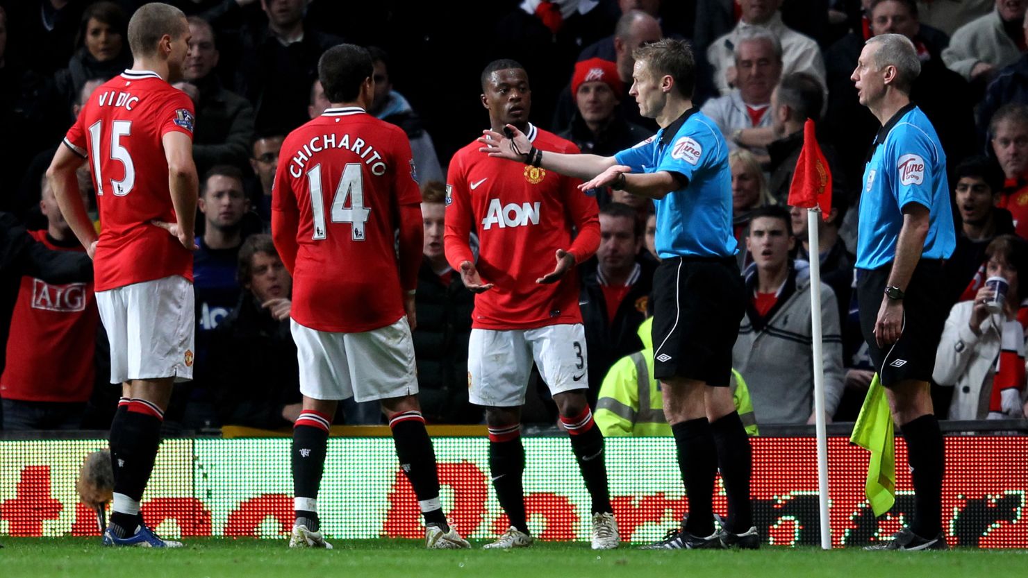 Ref Michael Jones gestures to the Manchester United players after consulting with his assistant and awarding a penalty.