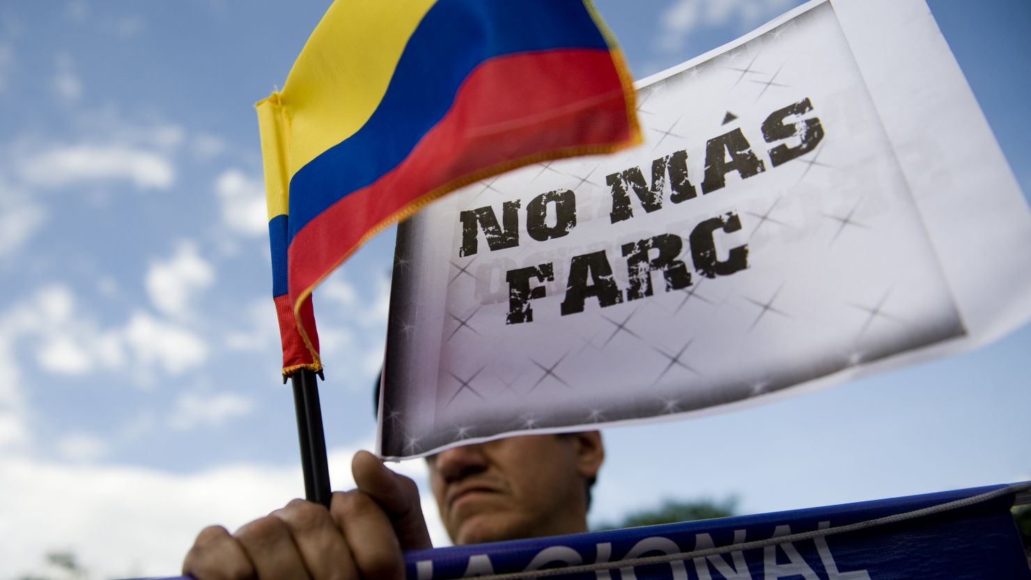 A man holds a Colombian flag with a sign that reads "No more FARC" on Wednesday, November 23, in Cali, Colombia.