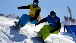 Two people participate in snowboarding. 
