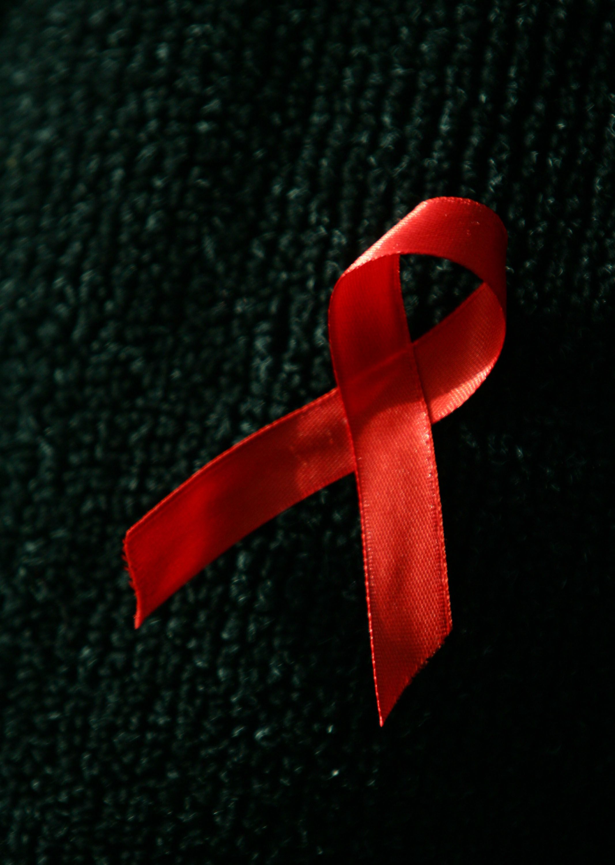 Premium Photo  A silk red ribbon in the form of a bow on a pink background  a symbol of the fight against aids and a sign of solidarity and support