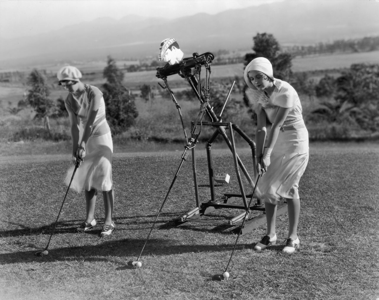 An early prototype robot was used to assist two women golfers with their swings in this 1925 picture.