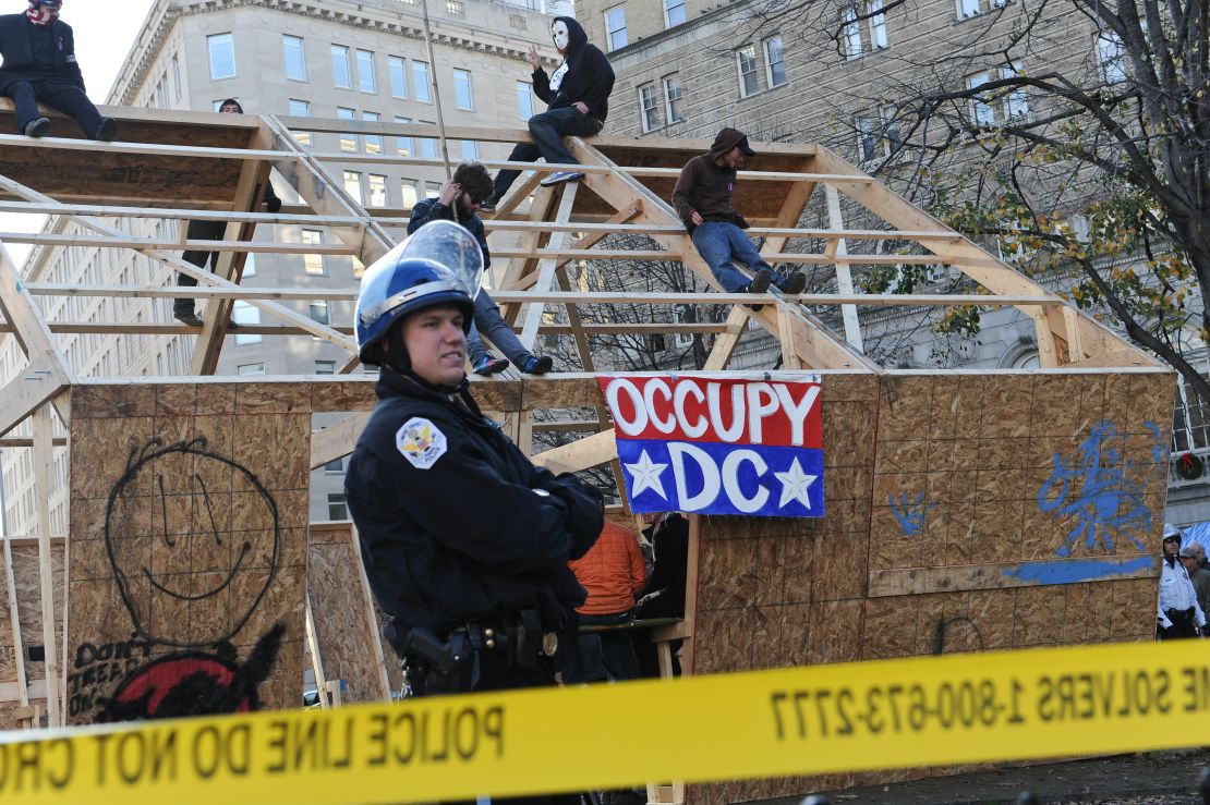 Occupy DC protesters sit atop a wooden structure  at their encampment in Washington's McPherson Square on Sunday.