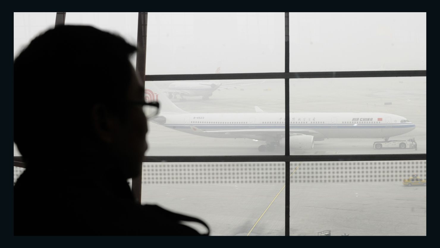 A  traveler at Beijing International Airport looks out at planes stranded due to thick fog, which caused widespread travel disruption