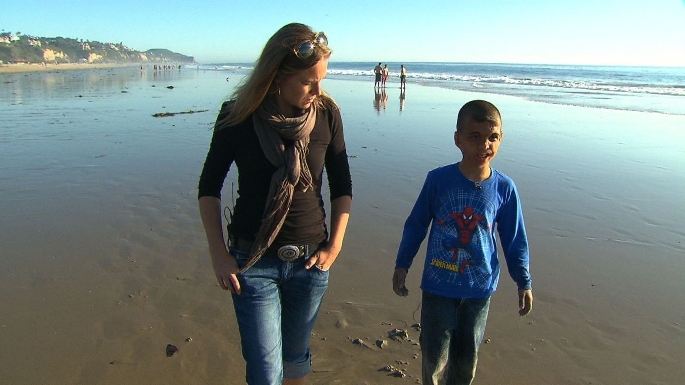 Youssif walks along a California beach in 2011 with CNN's Arwa Damon, who first told the boy's story in 2007.