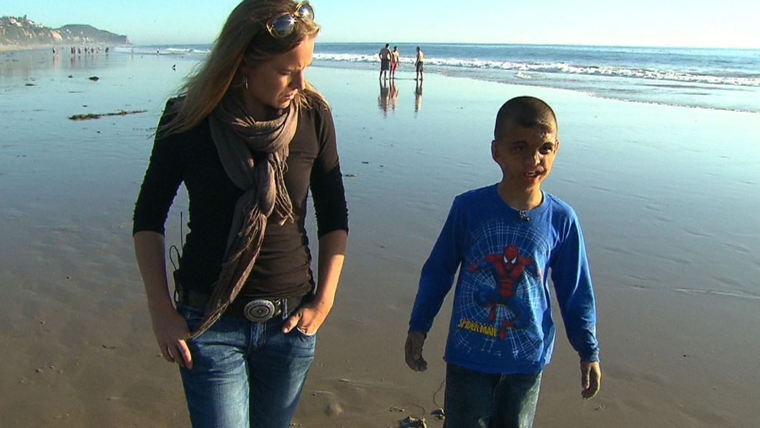 Youssif walks along a California beach with CNN's Arwa Damon, who first told the boy's story in 2007.