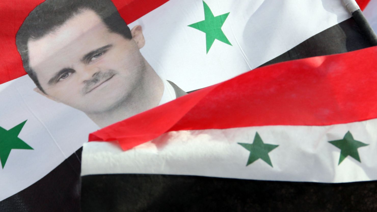  Pro-regime supporters hold up flag showing President al-Assad at a rally in Damascus, while opposition leaders warn of a brutal crackdown by the military.