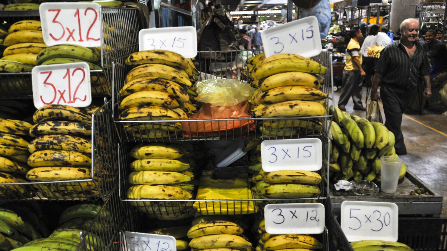 A man walks next to a banana stand in a public market in Caracas on May 06, 2011. Buying food has become a daily ordeal for many Venezuelans.