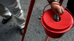 Donors put money in red Salvation Army kettle.