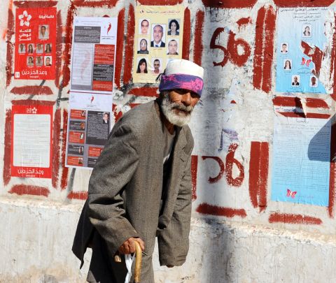 A beggar walks past election posters on October 19, 2011 in Tunis. Tunisians swore in a new president, secularist former human rights activist Moncef Marzouki on December 13. 
