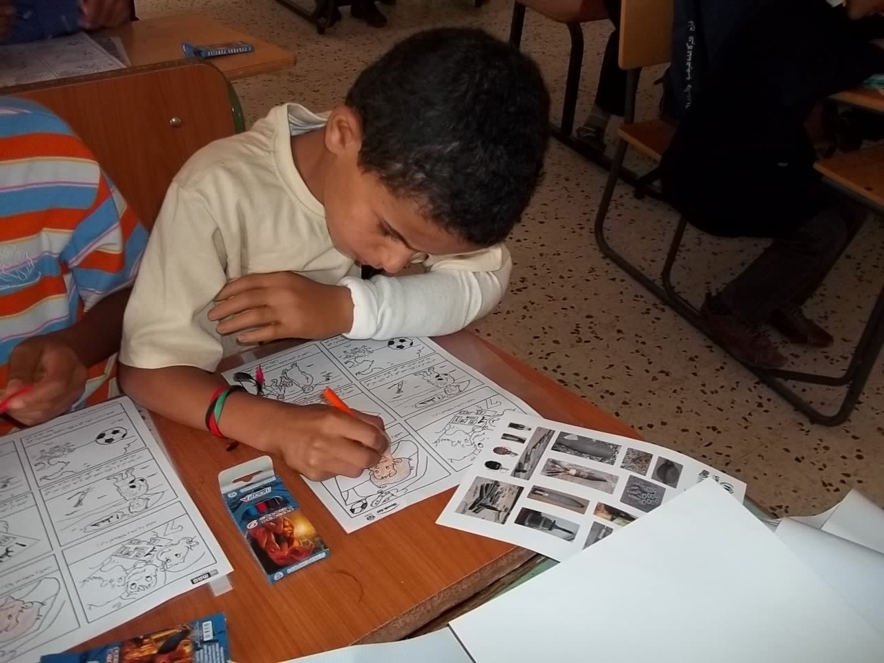 Mahmood with his new plastic hand, does coloring during a Risk Education session run by Mines Advisory Group.
